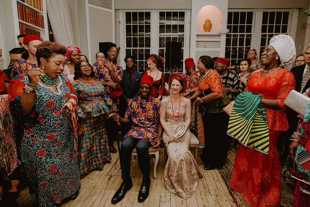 a just married couple sits in two chairs surrounded by wedding guests