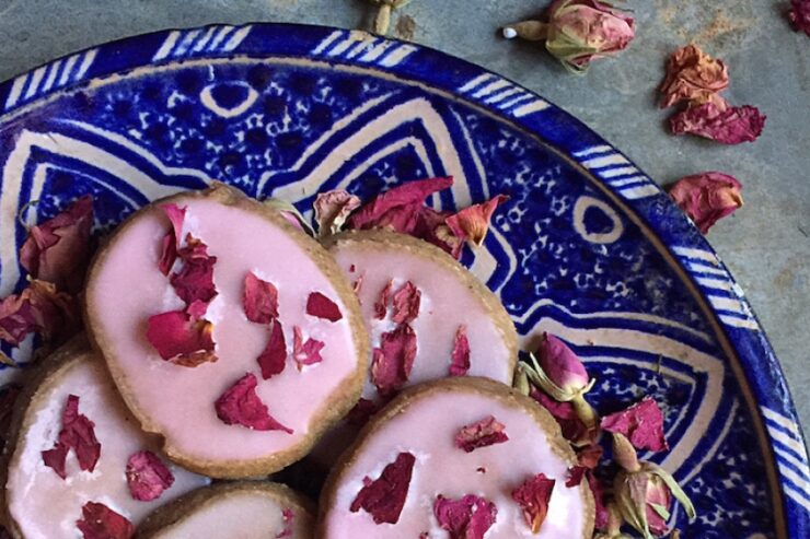 cookies with pink persian rose icing on a decorative blue plate