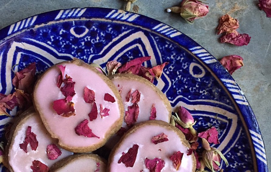 cookies with pink persian rose icing on a decorative blue plate