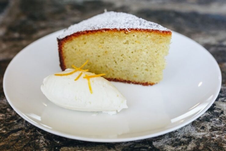 a slice of orange olive oil almond torte on a small white plate